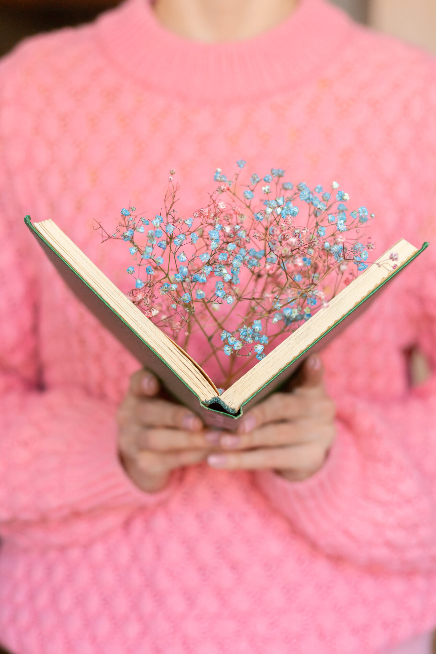 woman holding open book with bouquet dried flowers inside